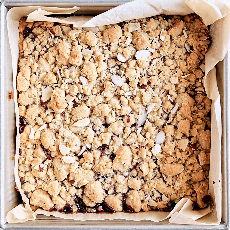 Baked crumb bars cooling in parchment-lined square baking pan