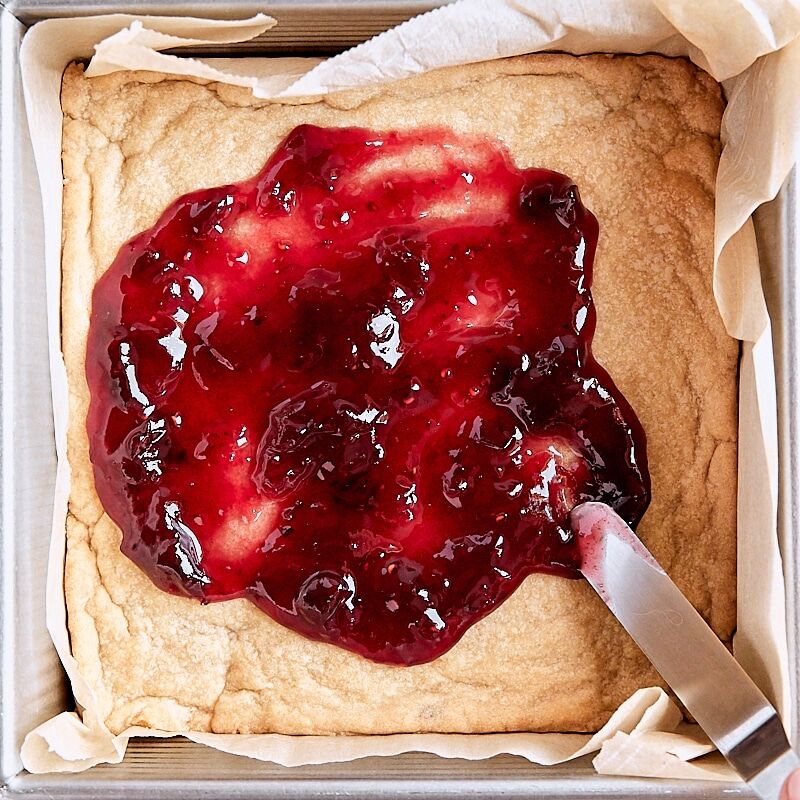 Jam filling added to crumb bars with an offset spatula