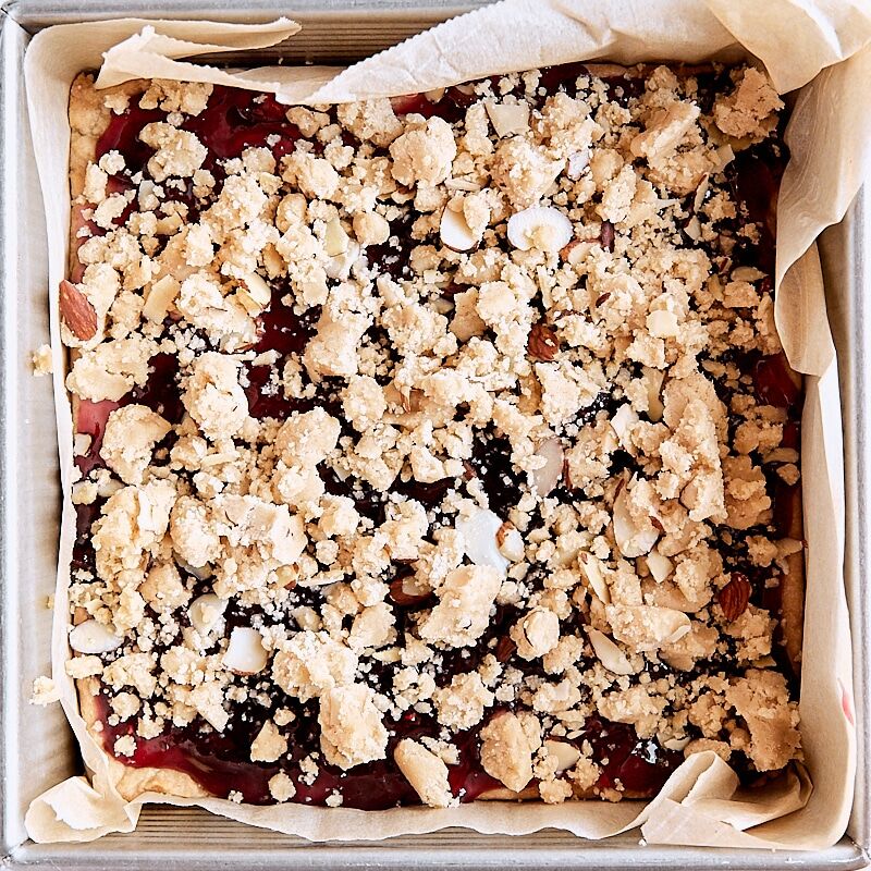 Assembled crumb bars in parchment-lined square baking pan