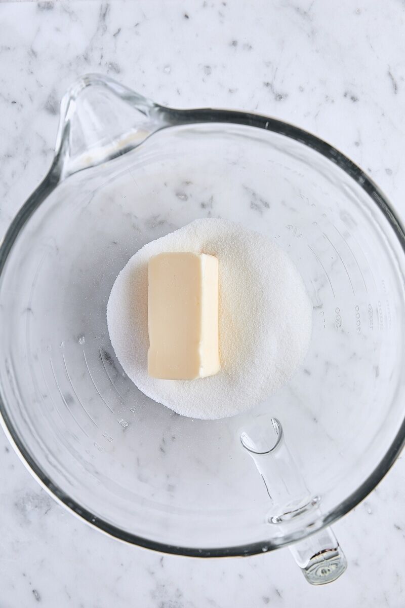 Room temperature butter and granulated sugar in glass mixing bowl