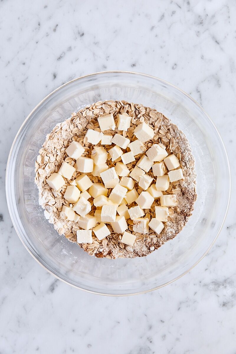 Cubed butter added to dry ingredients in glass bowl