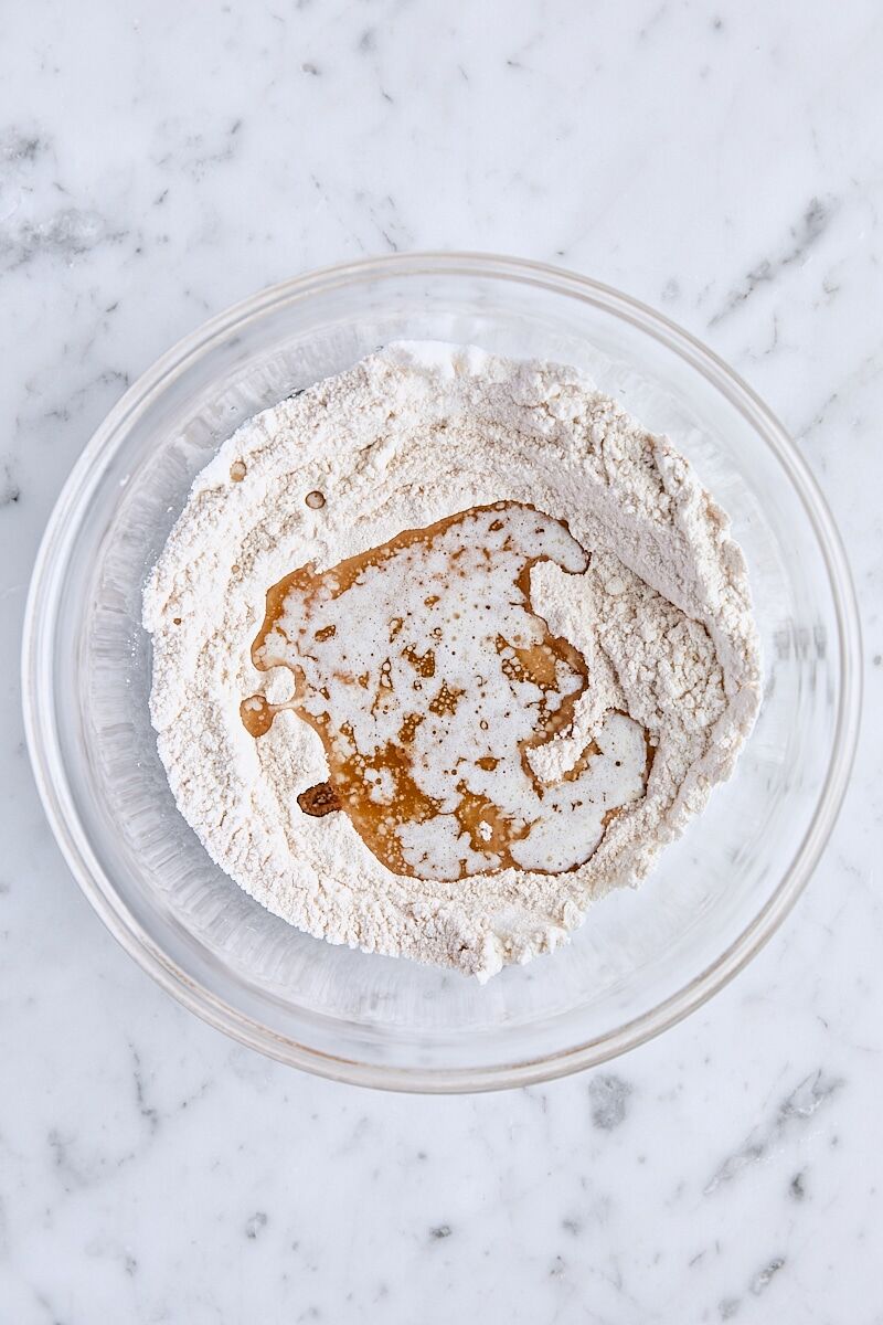 Melted butter and vanilla added to crumb topping ingredients in glass bowl