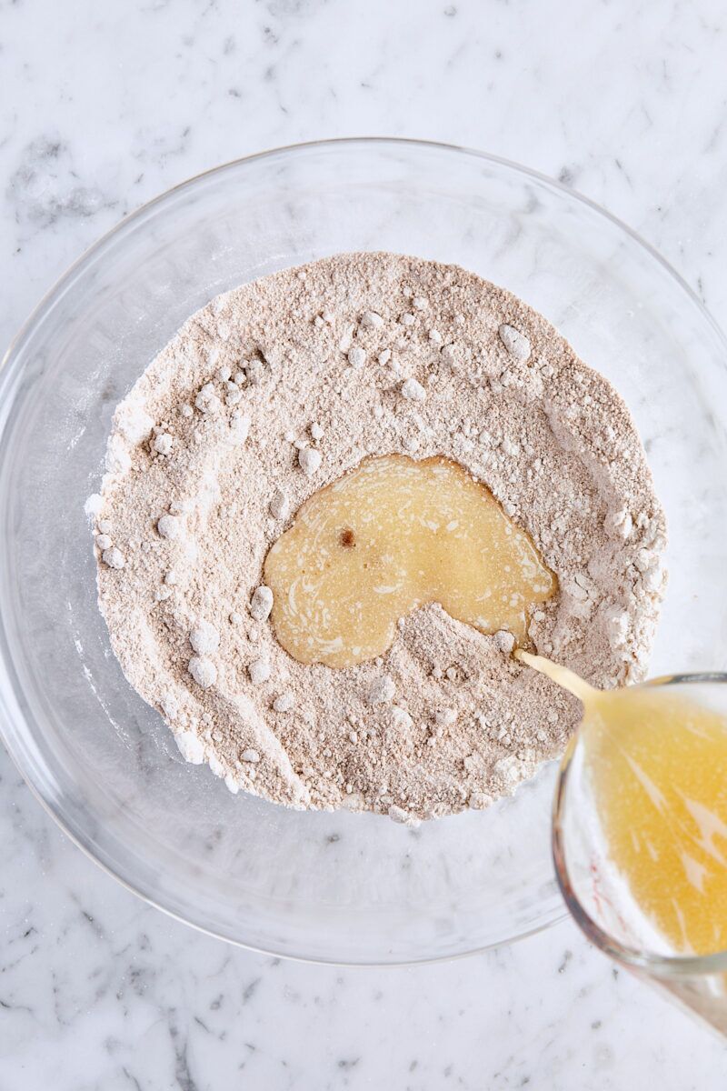 Melted butter added to streusel topping ingredients in glass bowl