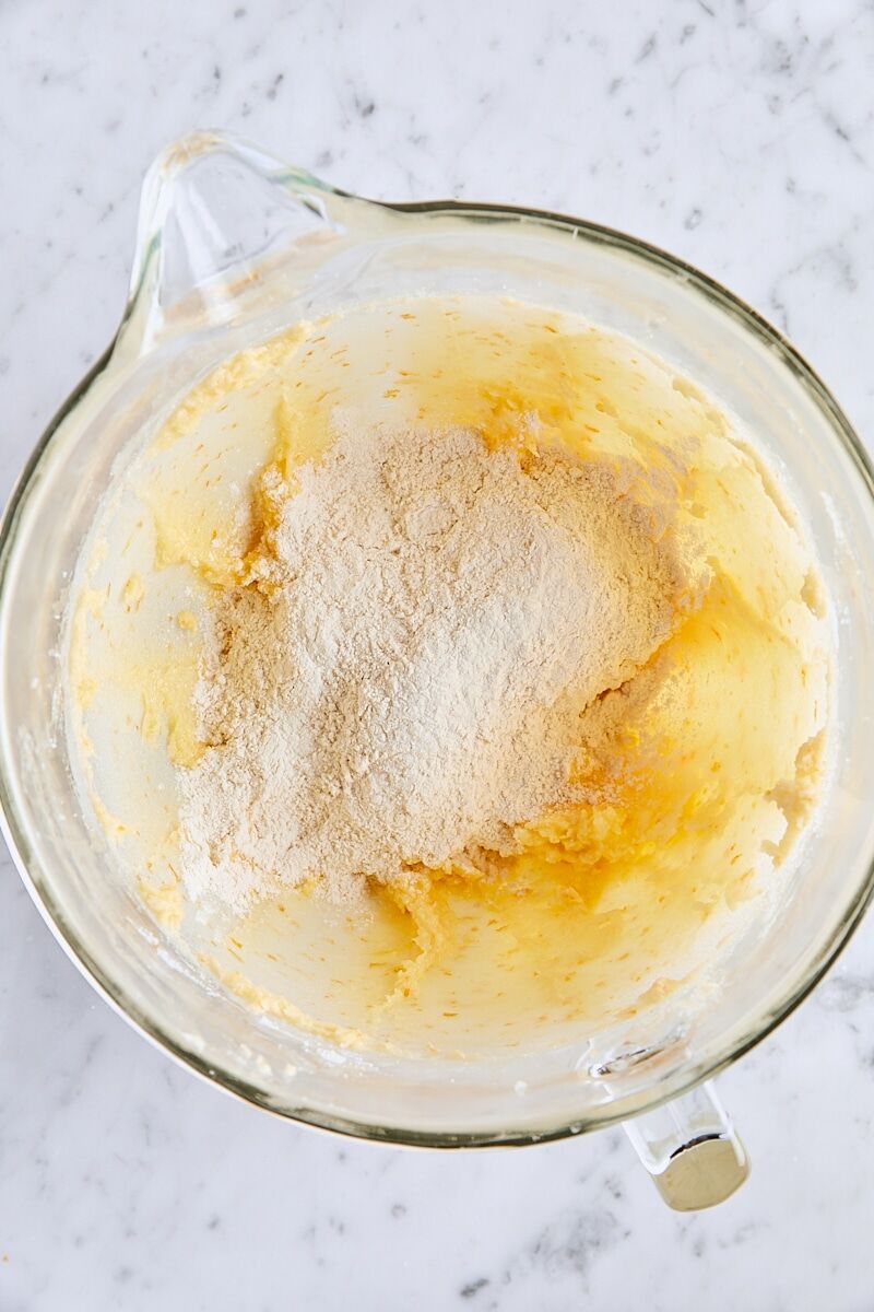 Dry ingredients added to cranberry snickerdoodle cookie dough in glass mixing bowl