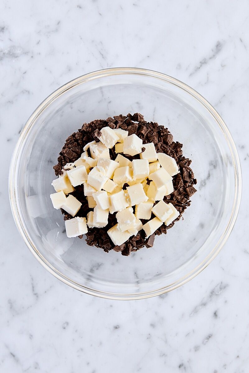 Cubed butter and chopped semisweet chocolate in small glass bowl