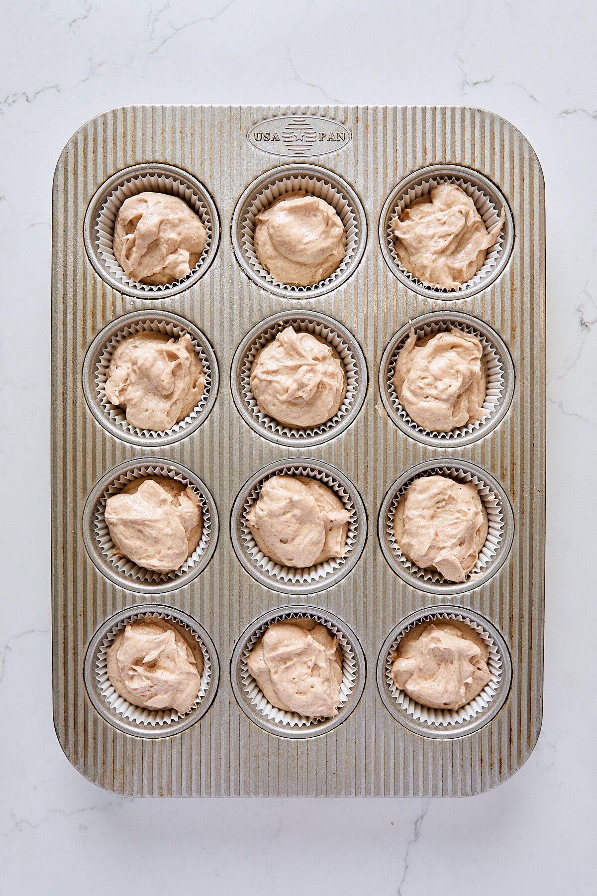 Donut muffin batter scooped into muffin tin