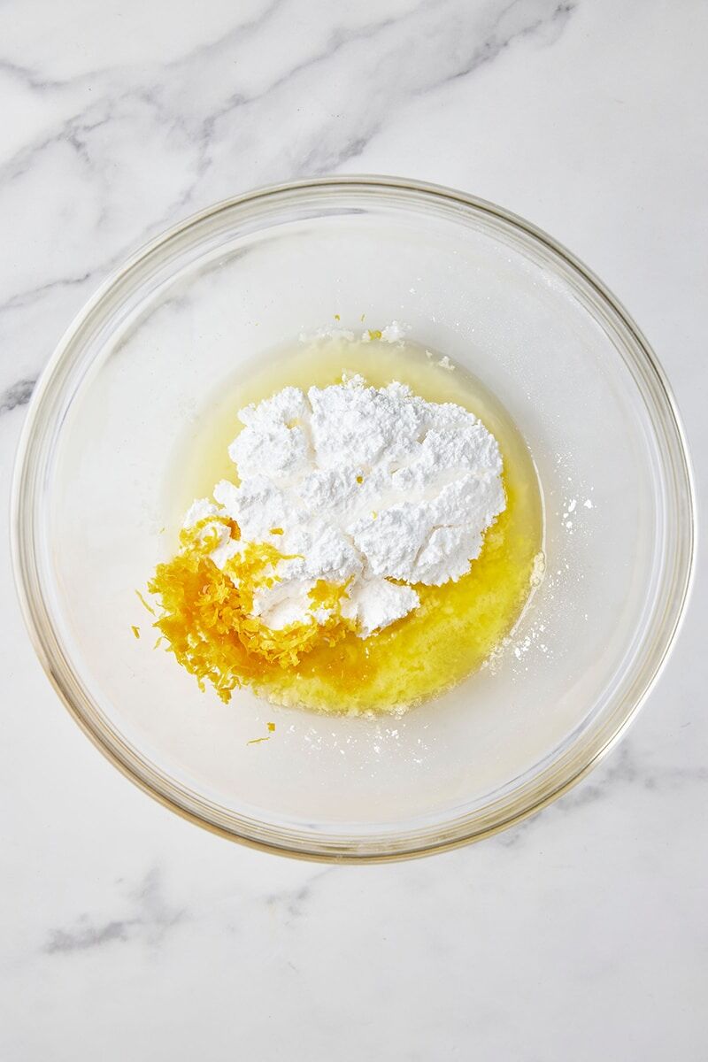 Melted butter, pinch of salt, lemon zest, lemon juice, and powdered sugar in glass bowl