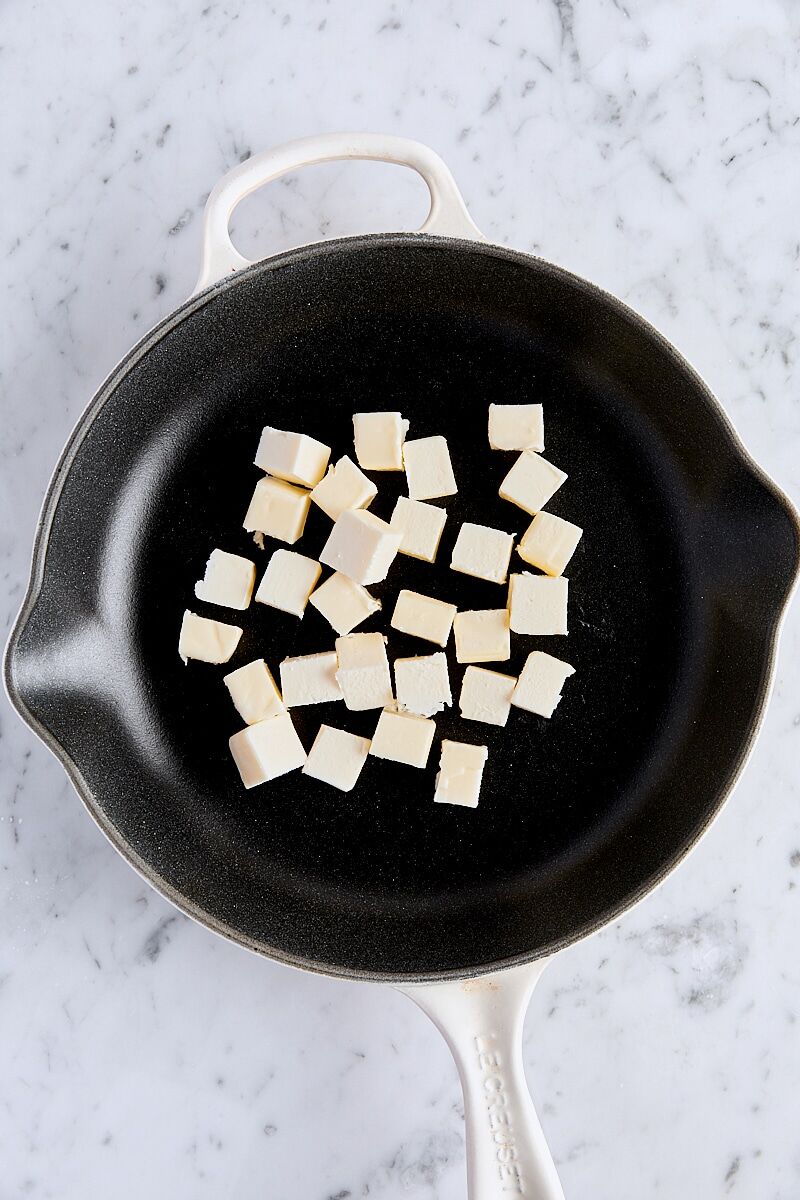 Cubed unsalted butter in cast iron skillet