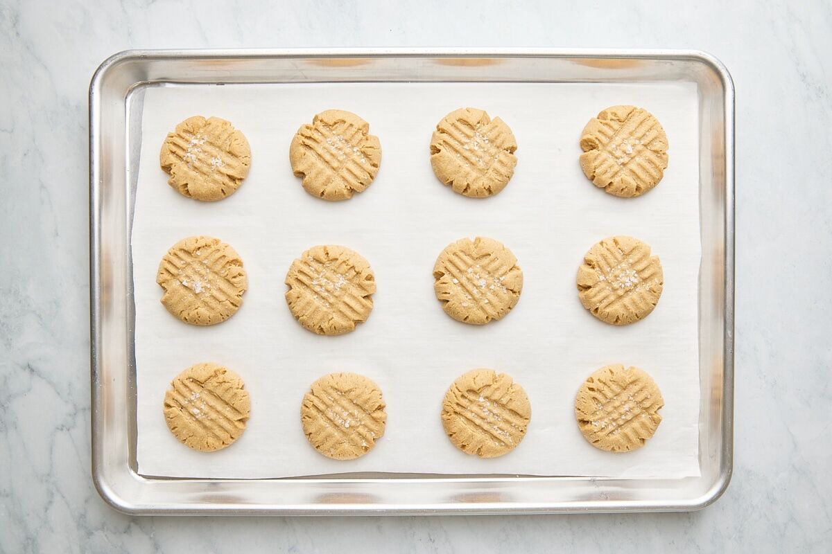 Baked cookies topped with flaky salt on parchment-lined baking sheet
