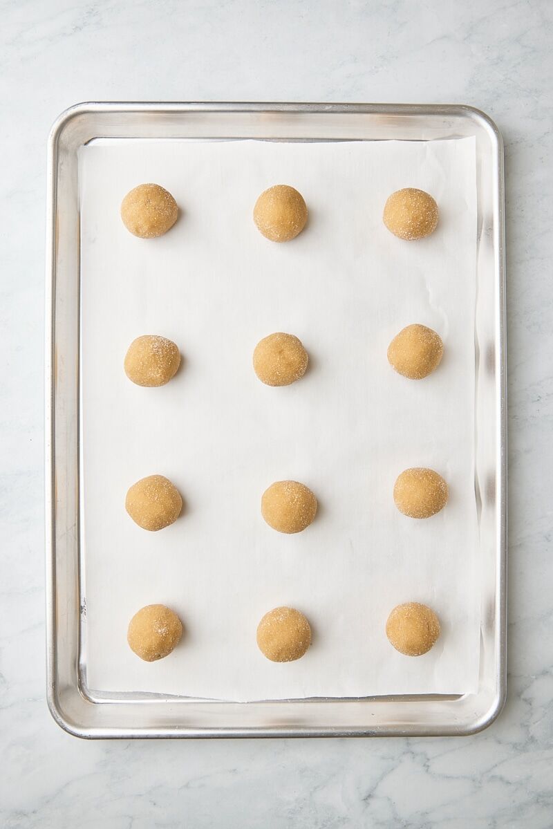 Peanut butter cookie dough balls scooped onto parchment-lined baking sheet