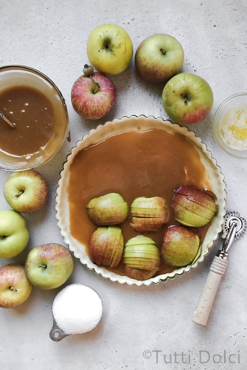 Unbaked tart shell filled with caramel sauce and sliced apples