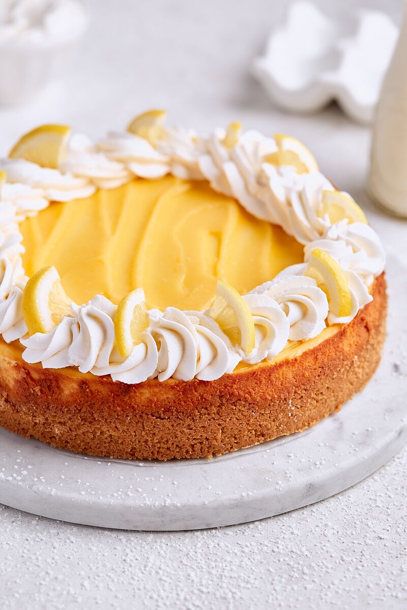Lemon Curd Cheesecake topped with homemade lemon curd, vanilla whipped cream, and lemon slices