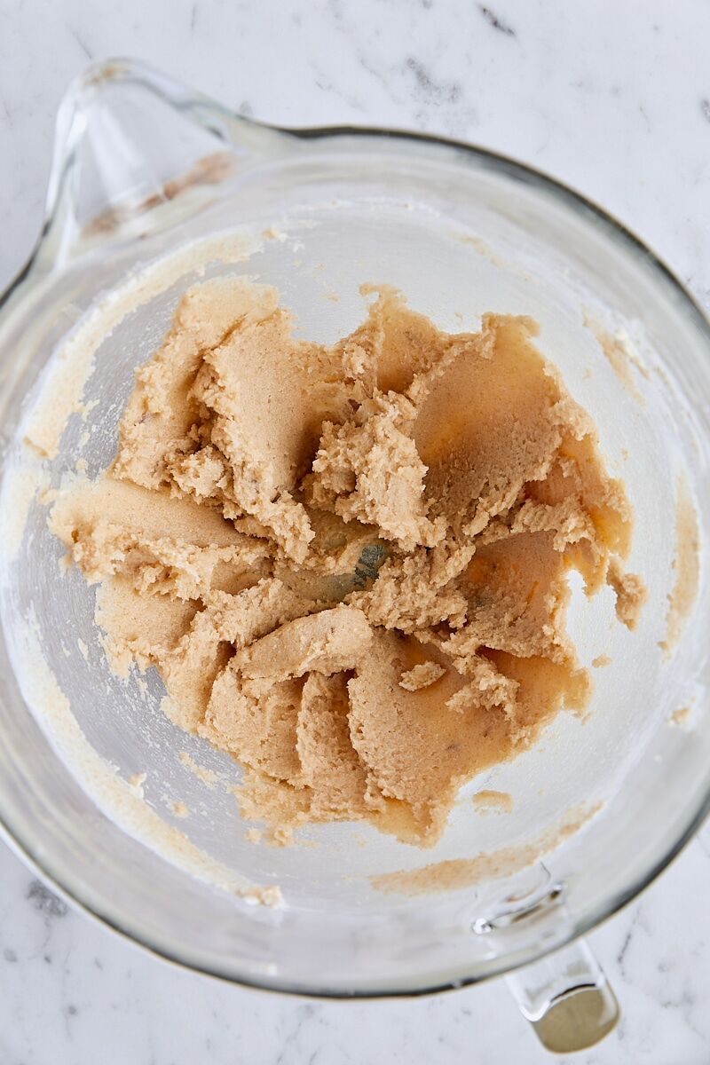 Softened butter and sugars mixed together in glass mixing bowl