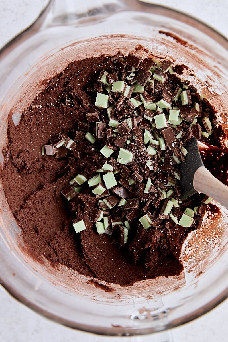 Chocolate mint cookie dough in glass mixing bowl with chopped Andes Creme de Menthe bar