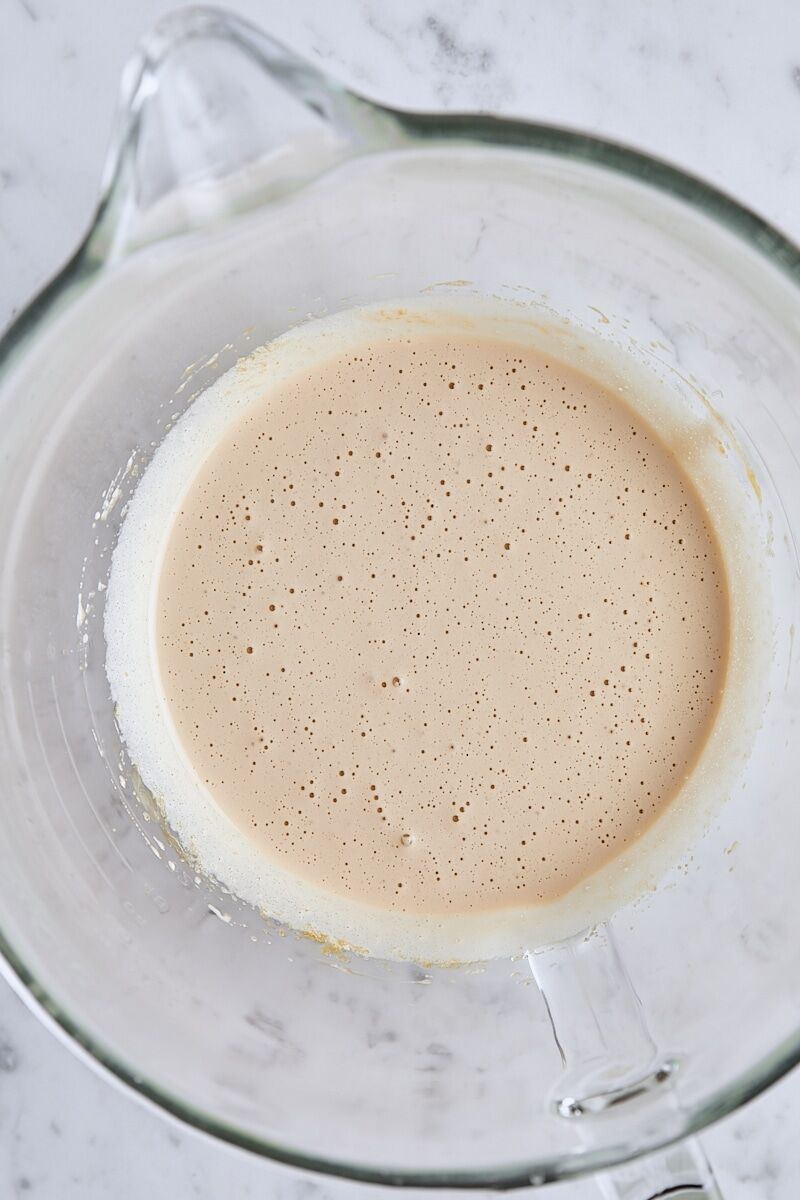Frothy whipped eggs and sugar in glass mixing bowl