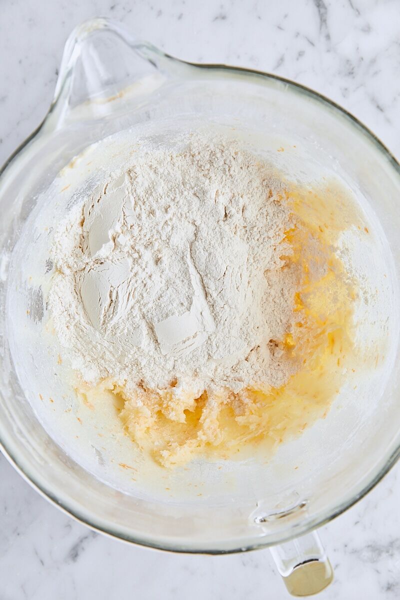 Flour added to shortbread dough in glass mixing bowl