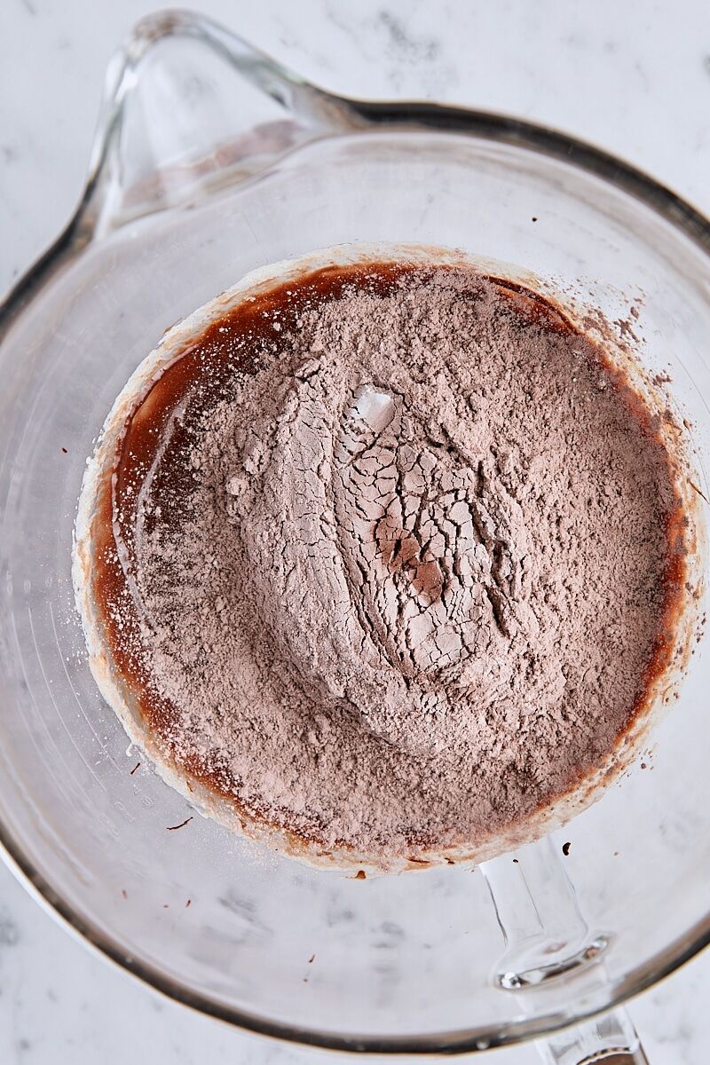 Flour added to chocolate batter in glass mixing bowl