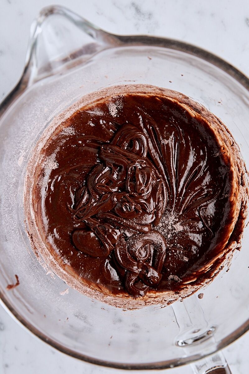 Flour mixed into brownie cookie dough in glass mixing bowl