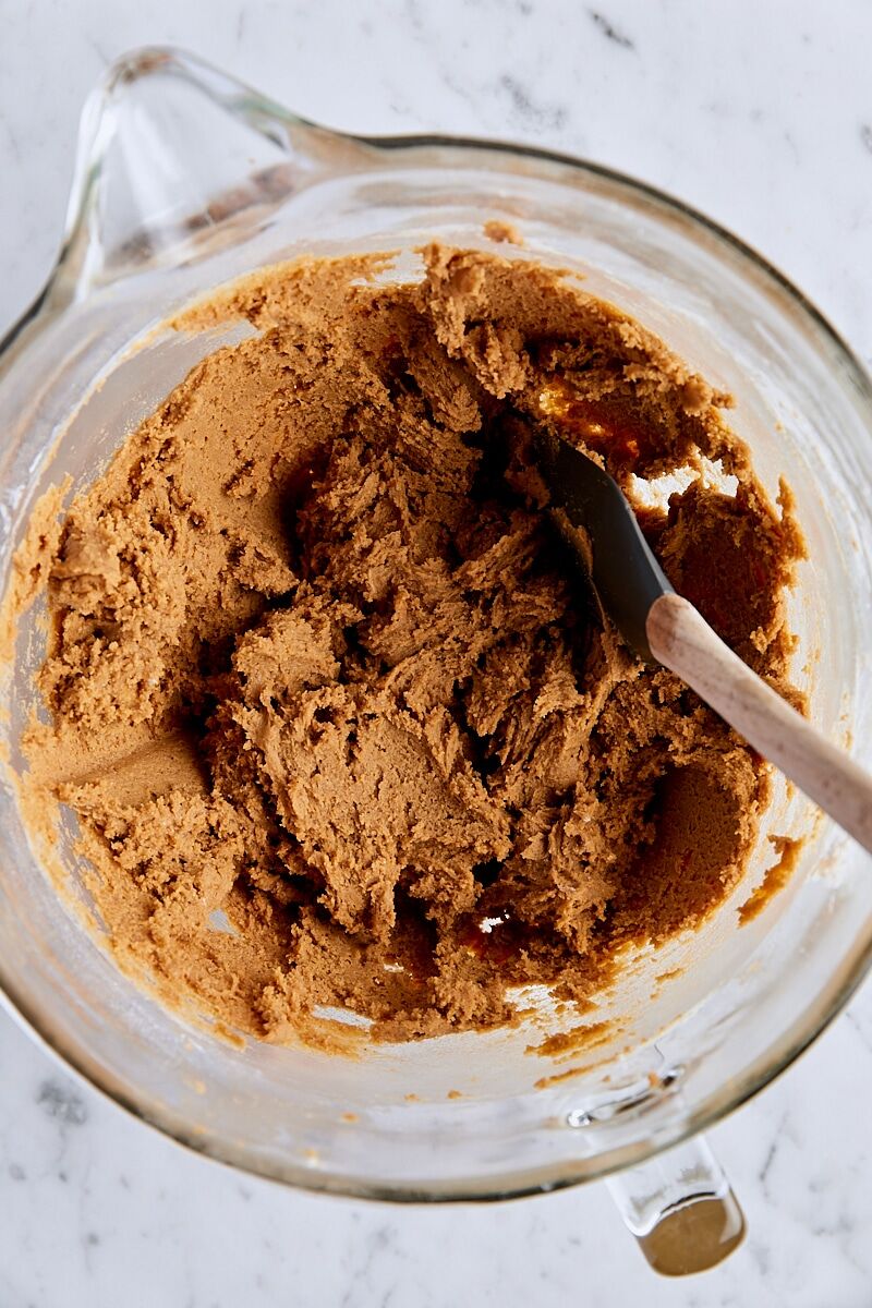 Molasses spice dough in glass mixing bowl with spatula
