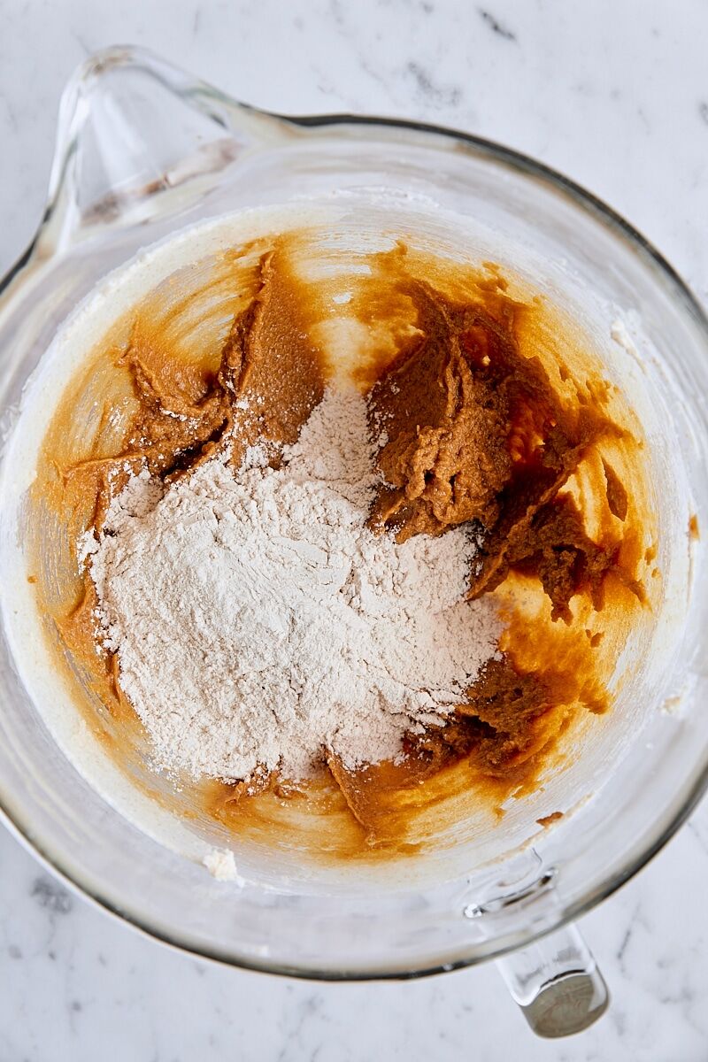 Dry ingredients added to molasses spice cookie dough in glass mixing bowl