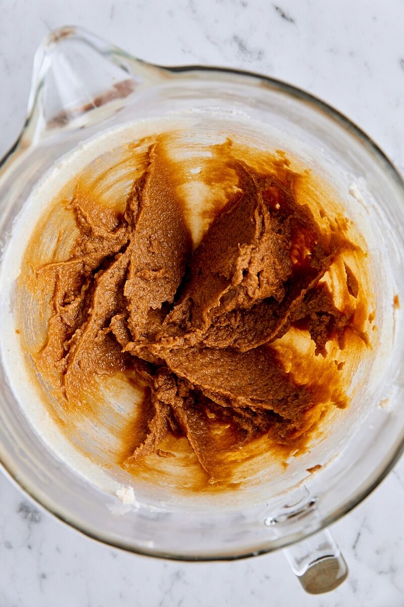 Wet ingredients added to molasses spice cookie dough in glass mixing bowl