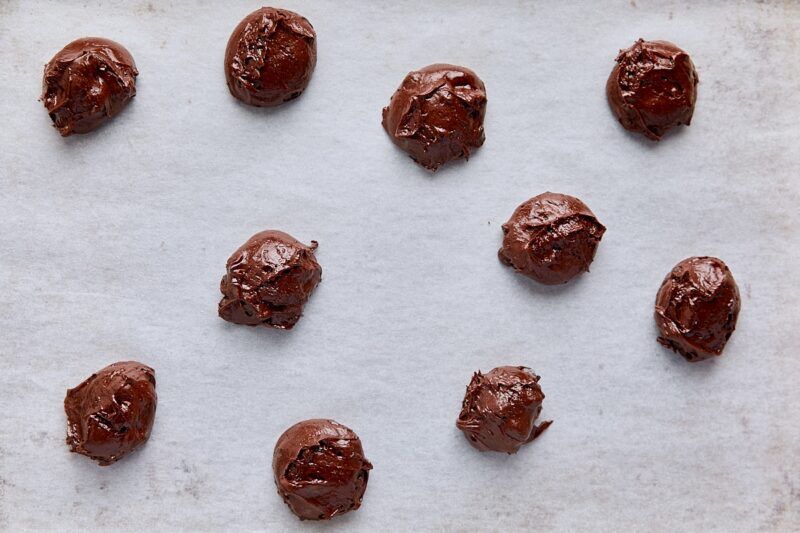 Scooped brownie cookie dough on parchment-lined baking sheet
