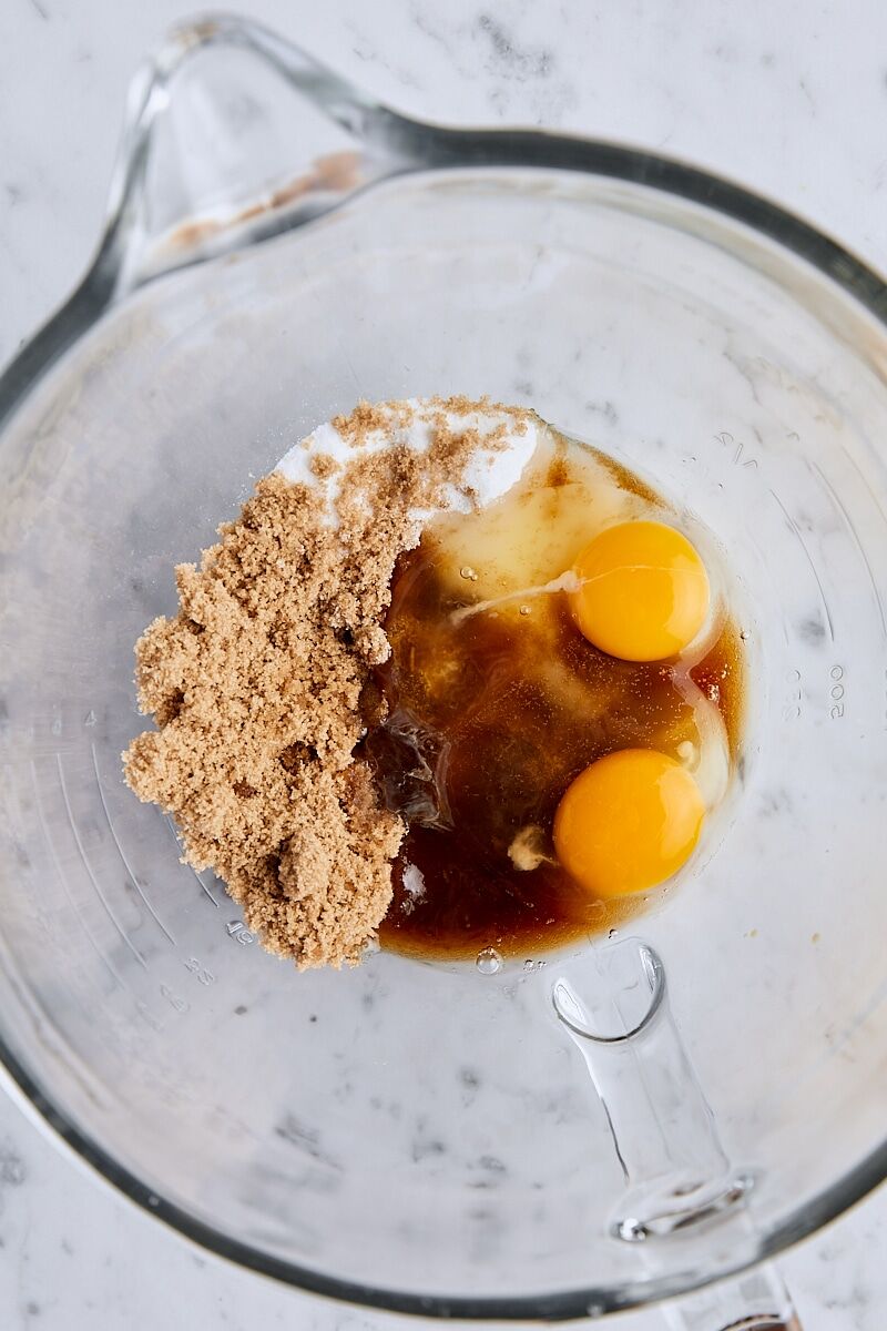 Granulated sugar, brown sugar, and eggs in glass mixing bowl