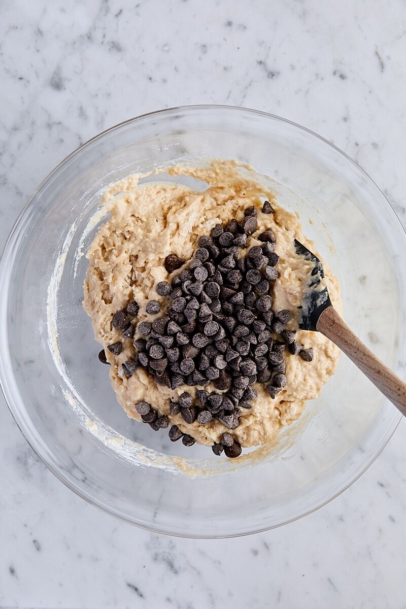 Chocolate chips added to batter in glass bowl with spatula