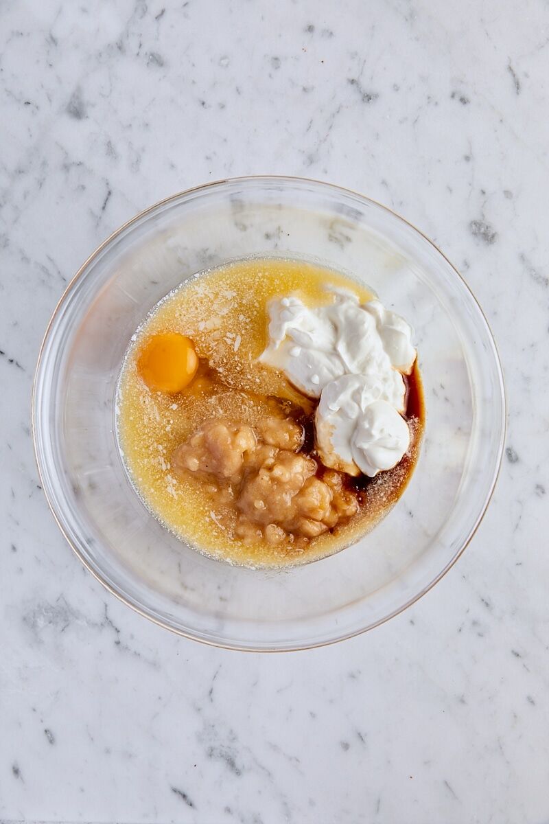 Mashed banana, Greek yogurt, melted butter, large egg, and vanilla extract in glass bowl