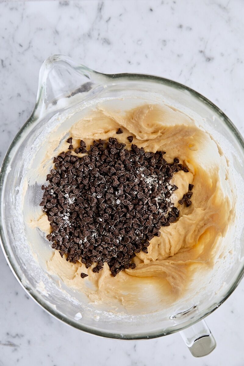 Mini chocolate chips added to batter in glass mixing bowl