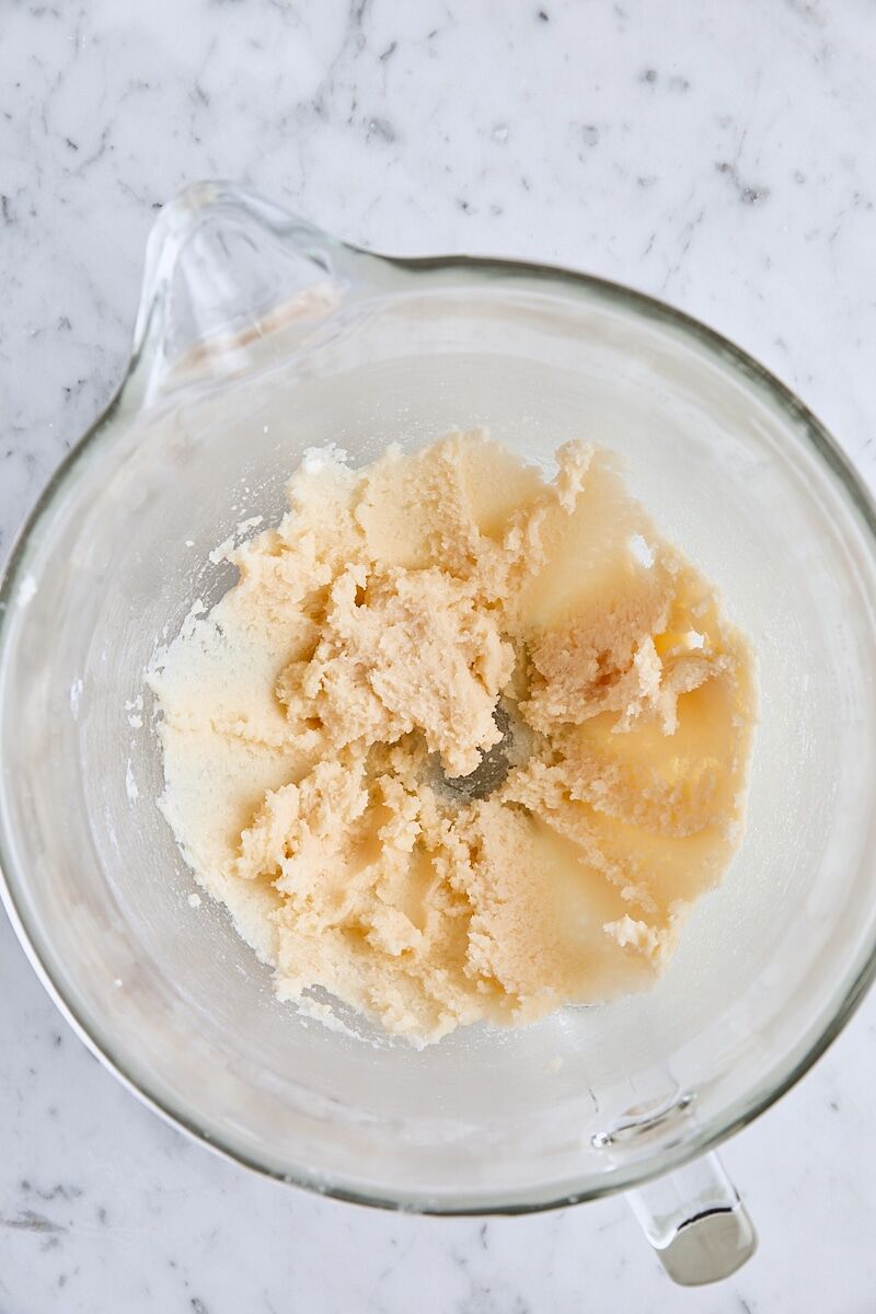 Vanilla and almond extracts mixed with butter and sugar in glass mixing bowl