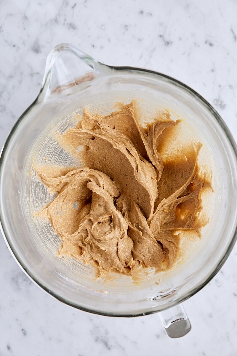 Eggs and egg yolk mixed into batter in glass mixing bowl