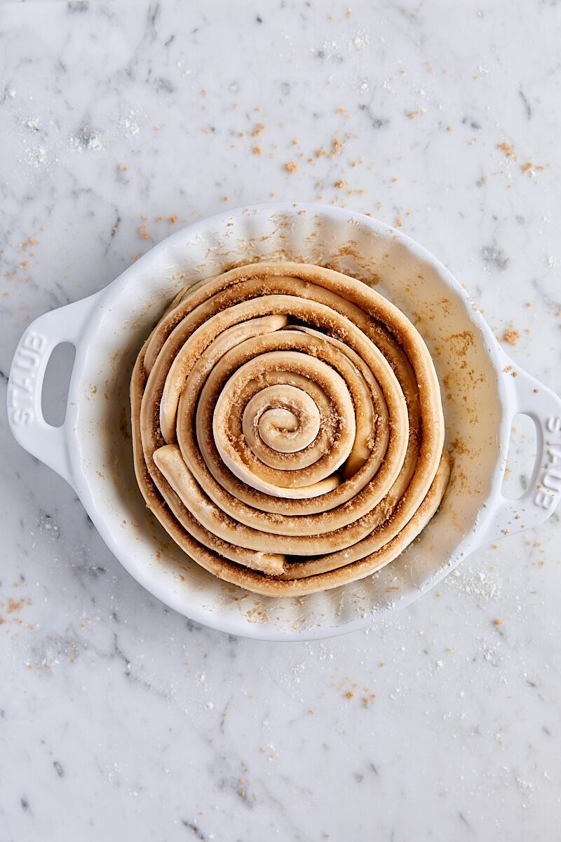 Giant cinnamon roll assembled in white ceramic baking dish