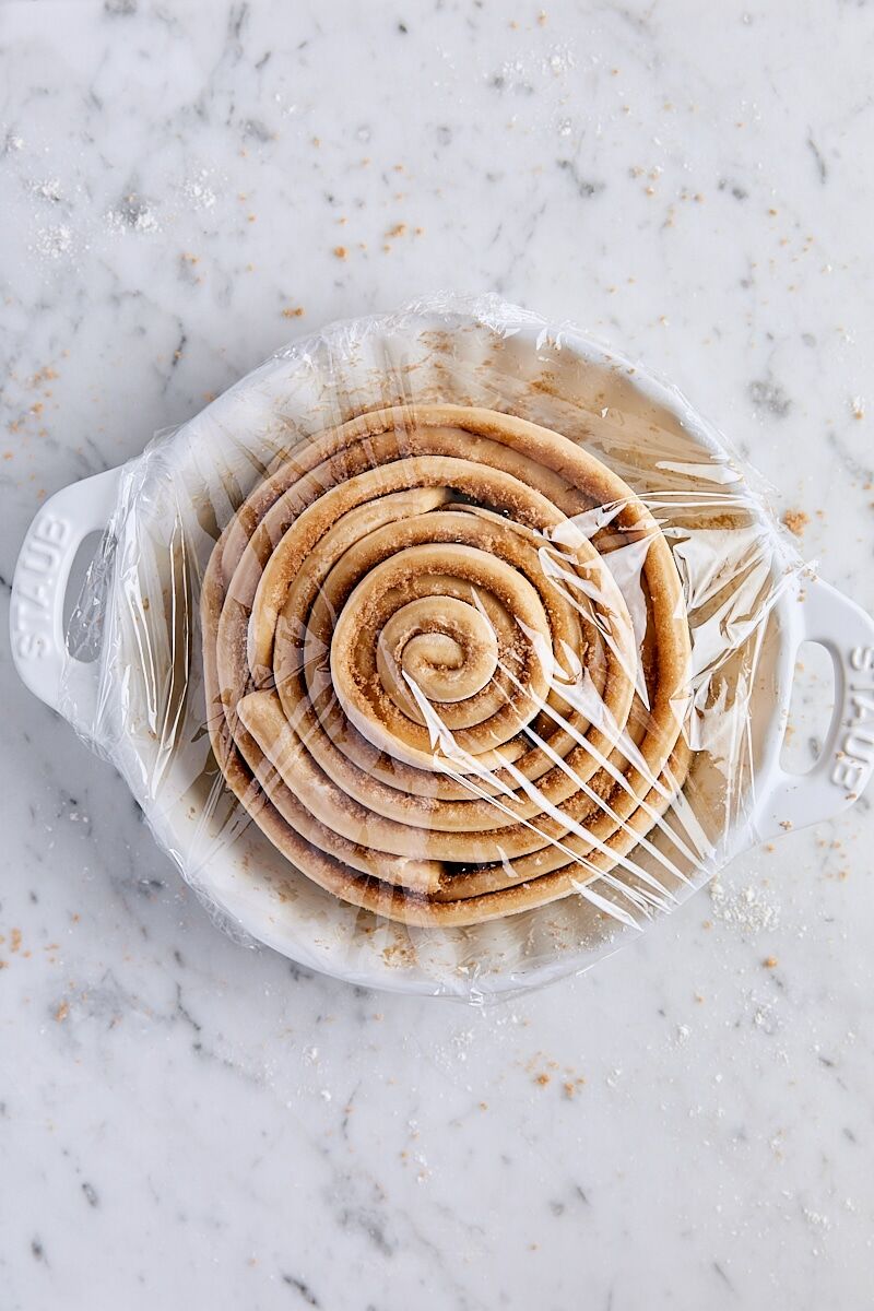 Unbaked giant cinnamon roll in white ceramic baking dish