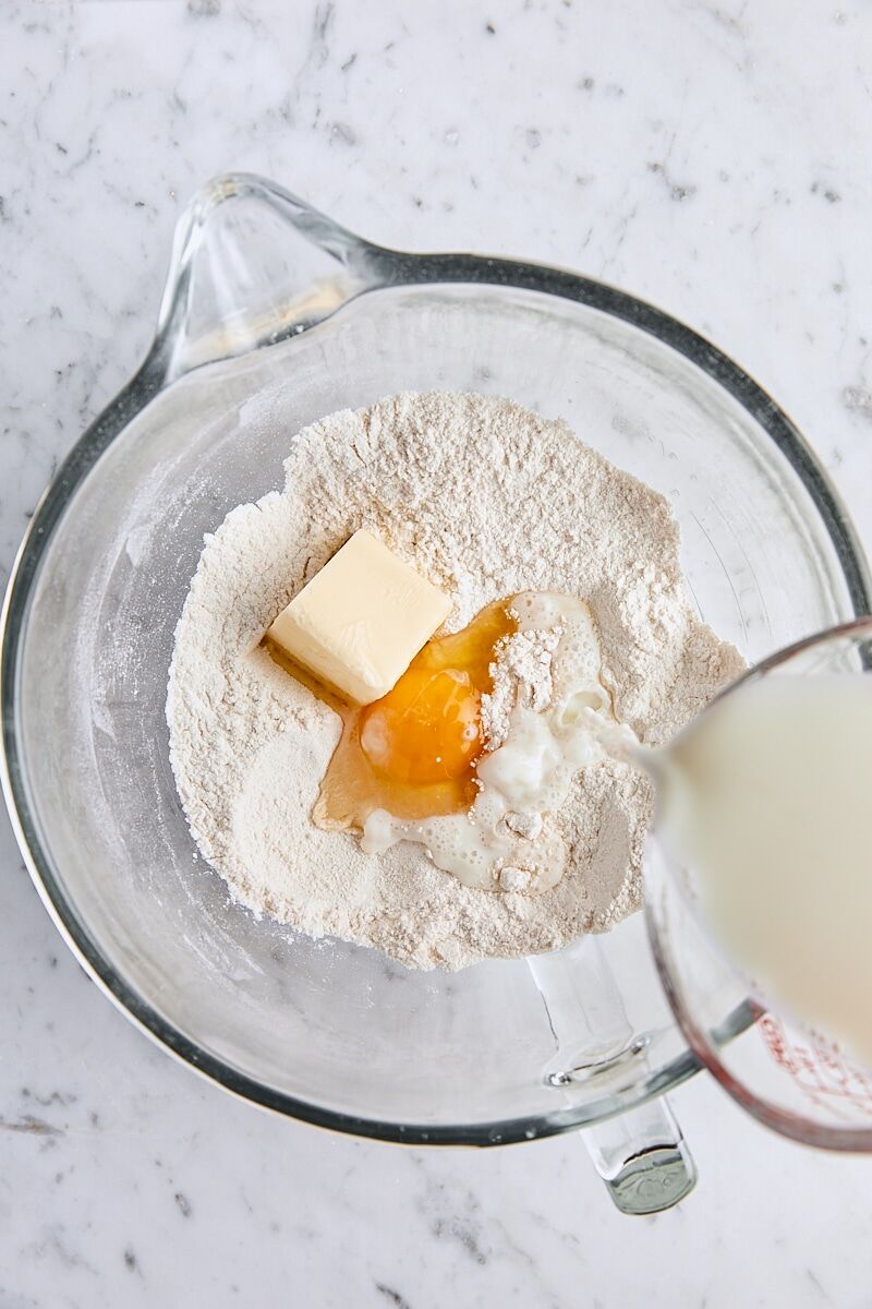 Warm milk, butter, and egg added to dry ingredients in glass mixing bowl