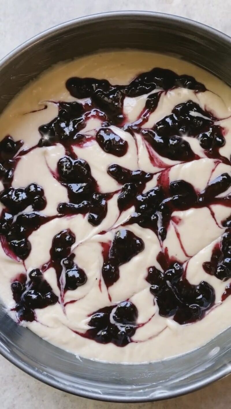 Crumb cake batter in springform pan with blueberry swirl