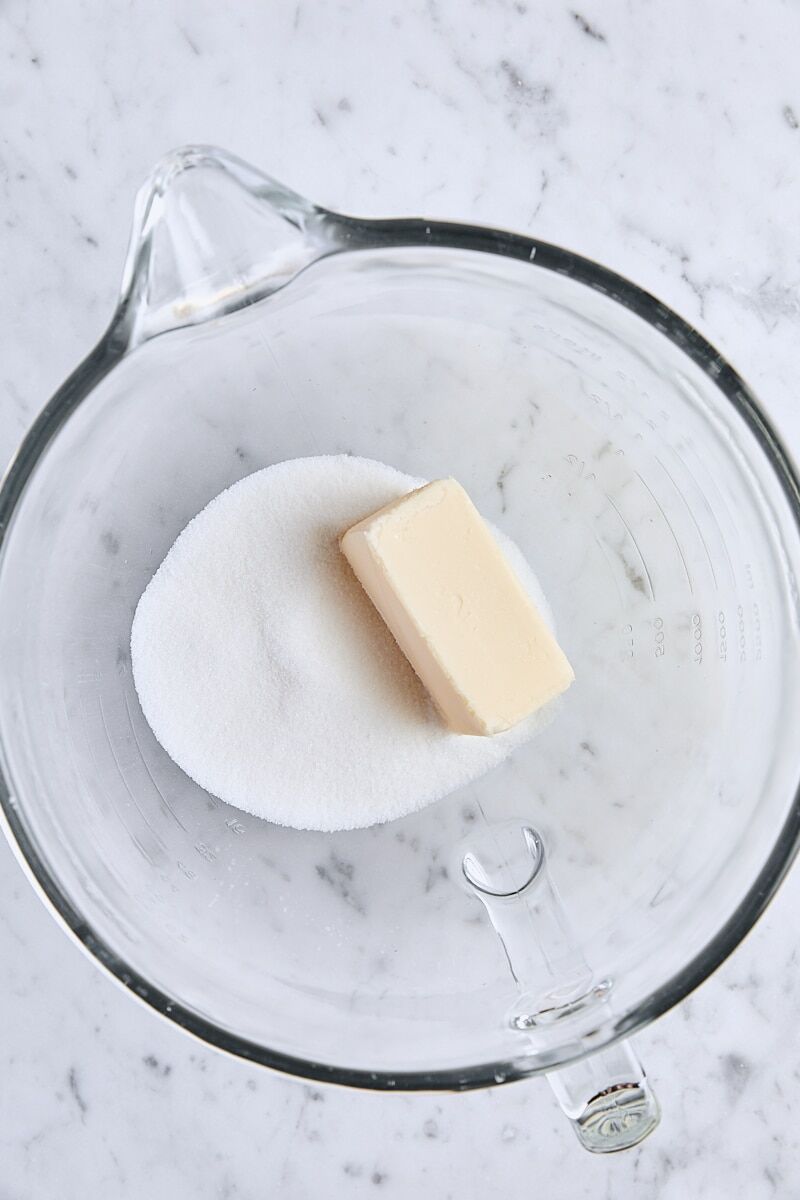Room temperature butter and granulated sugar in glass mixing bowl