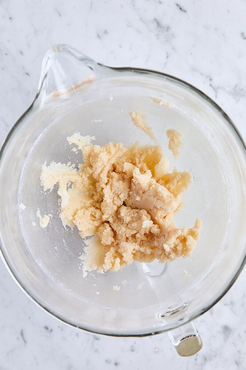 Vanilla and almond extracts mixed with butter and sugar in glass mixing bowl
