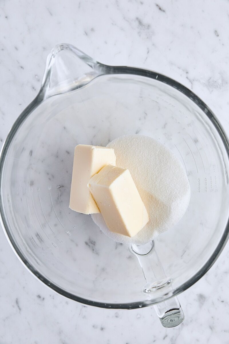 Room temperature butter and granulated sugar in glass mixing bowl