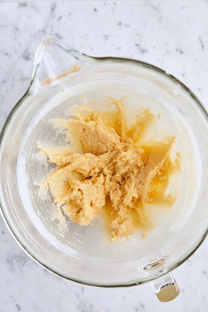 Egg and vanilla mixed with butter and sugar in glass mixing bowl