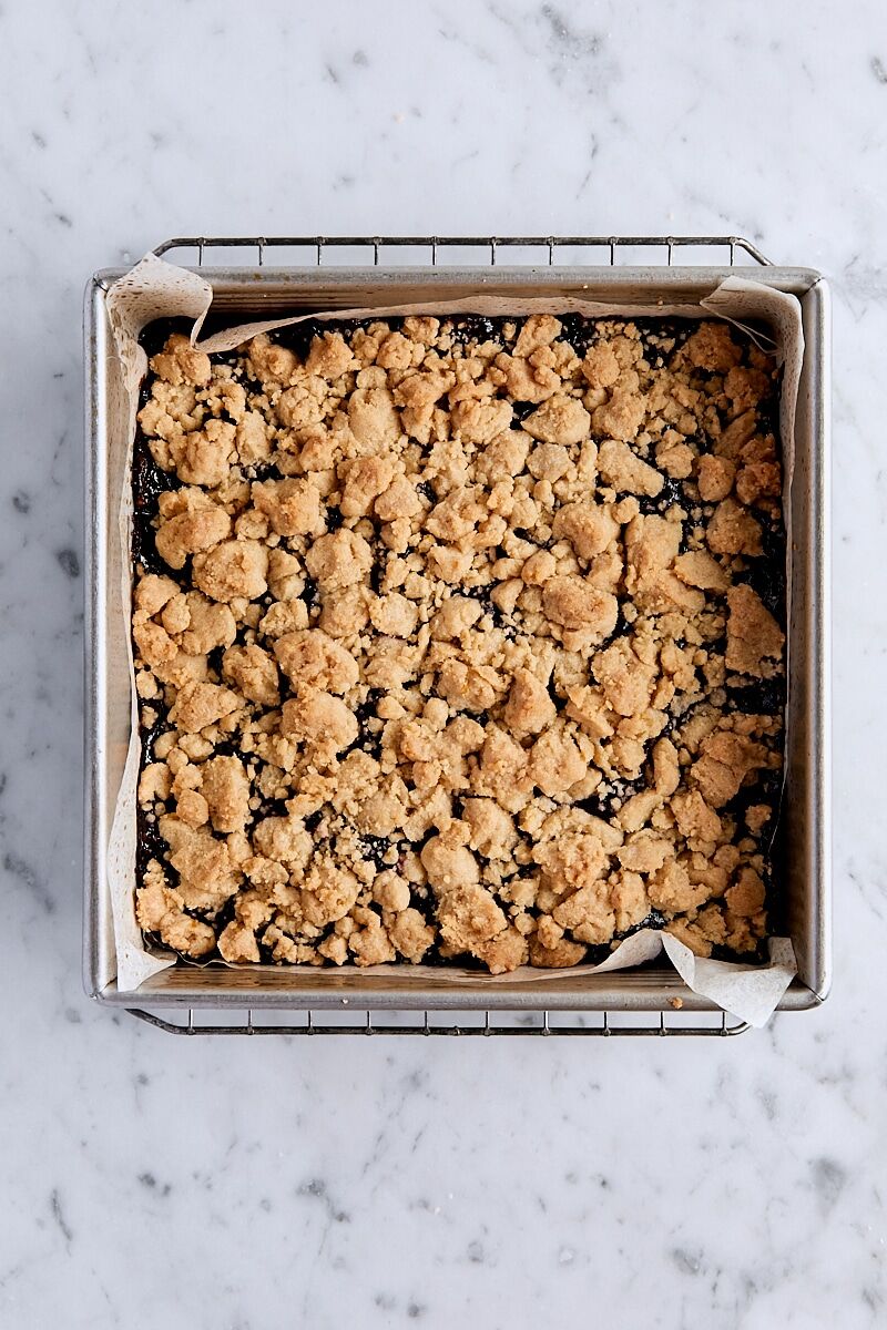 Baked blackberry crumb bars in parchment-lined baking pan