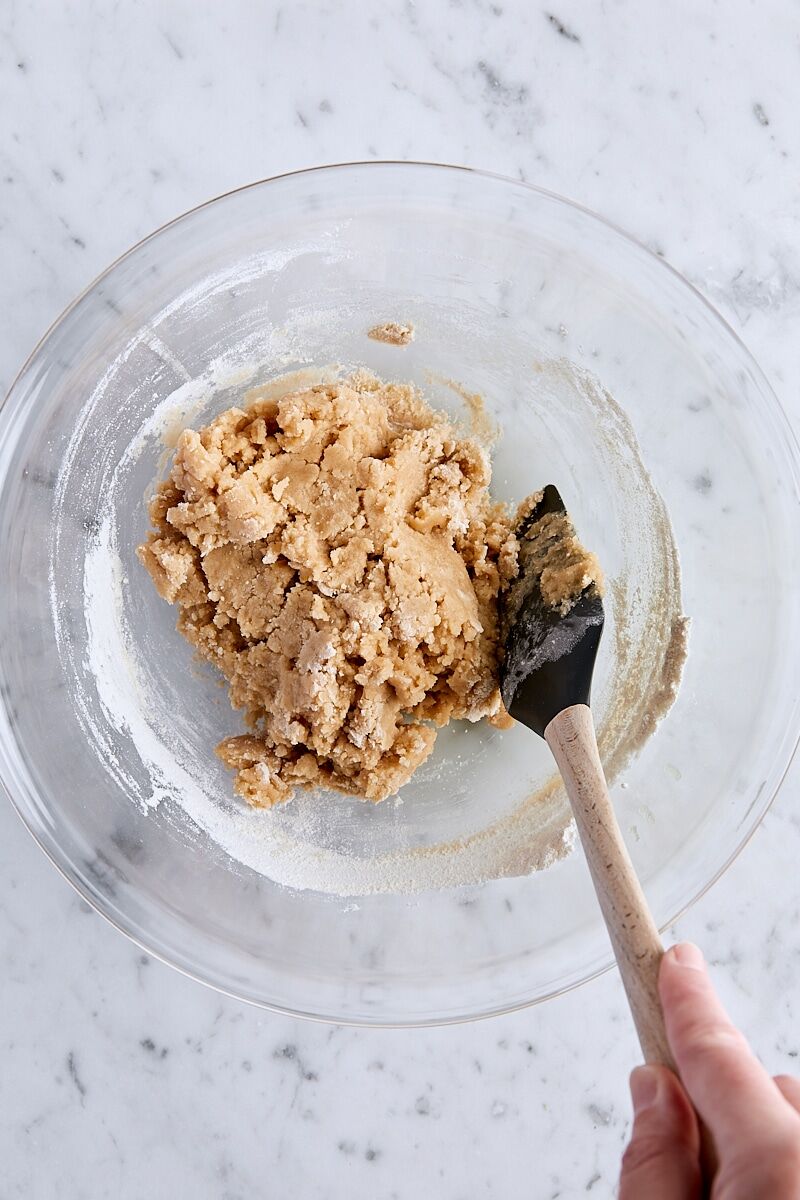 Crust and crumble dough folded together in large glass bowl with spatula