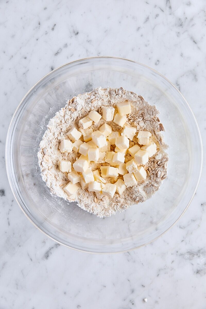 Cubed butter added to dry ingredients in glass bowl
