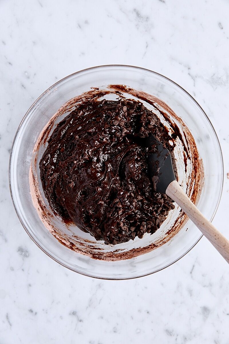 Mixed brownie batter in glass bowl with spatula