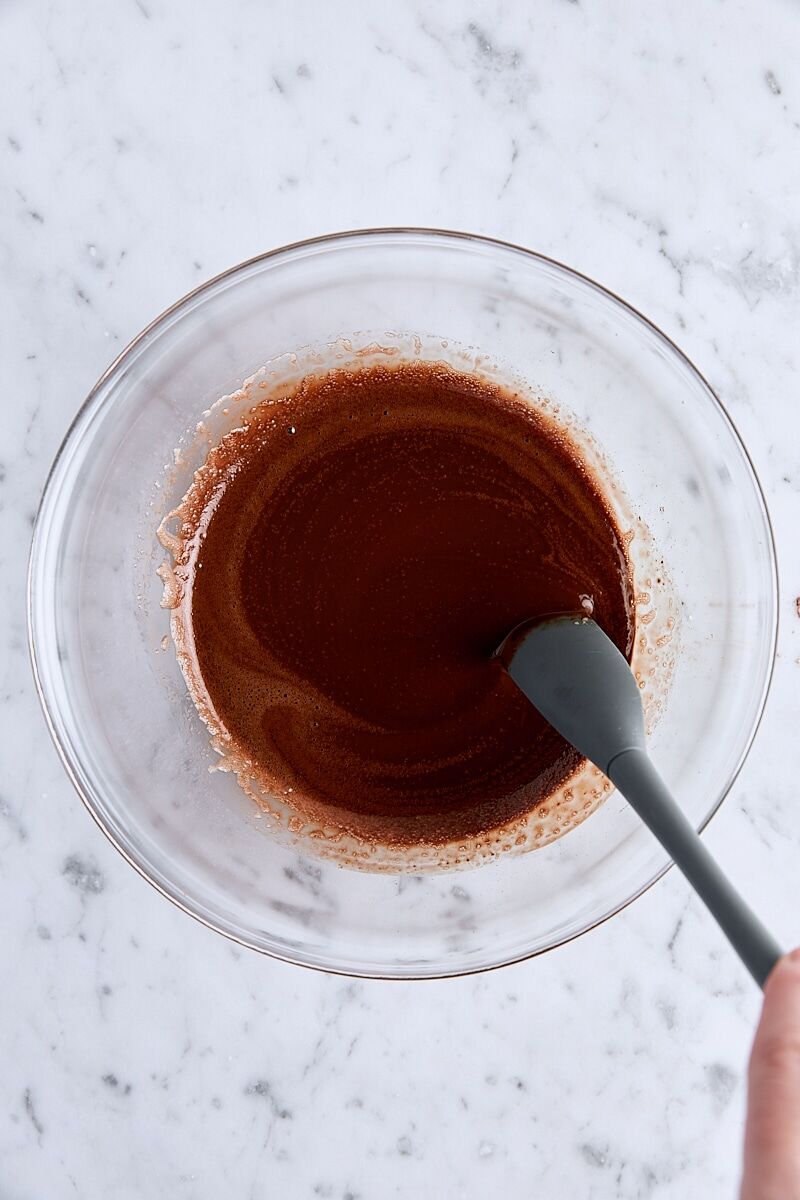Brown butter and melted chocolate stirred together in glass bowl with spatula