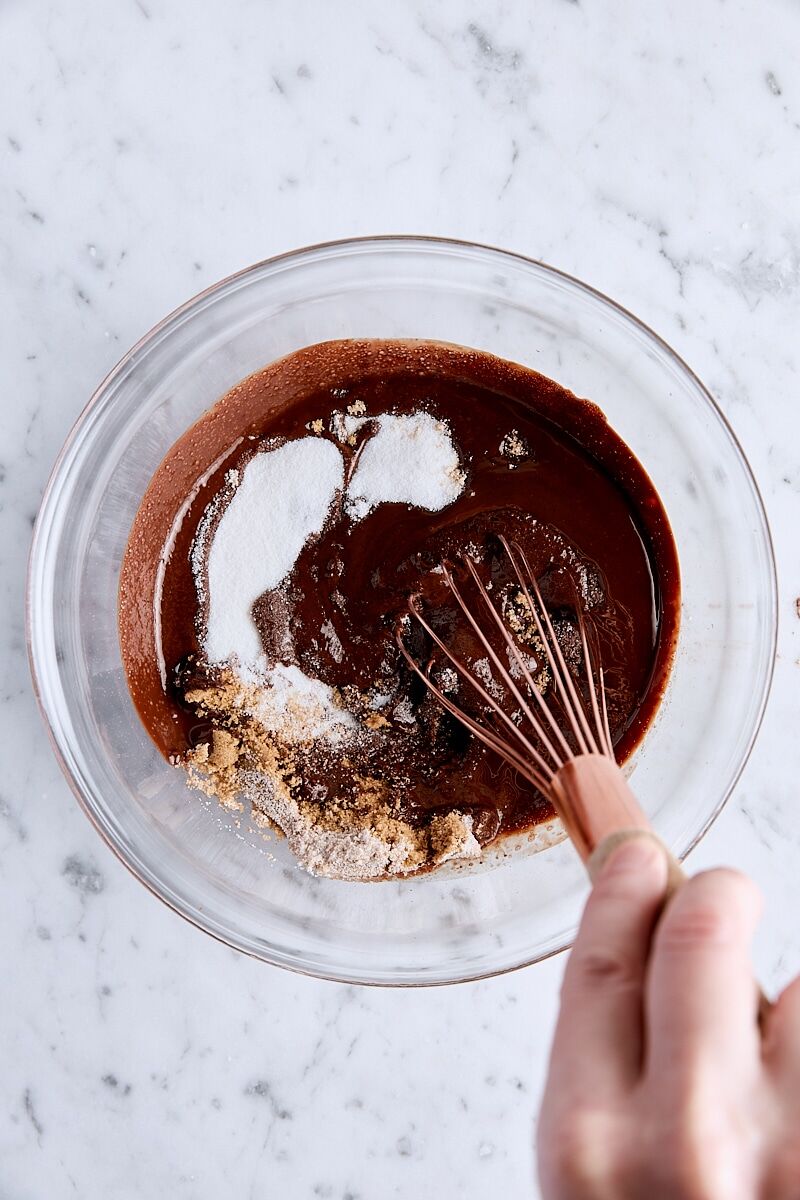 Sugars whisked into melted chocolate mixture in glass bowl