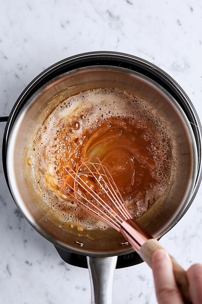 Butter whisked into caramel mixture in light-colored saucepan