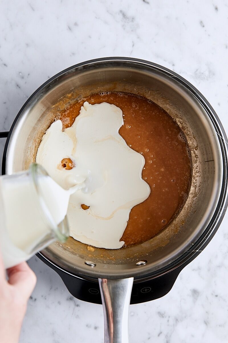 Heavy cream added to caramel mixture in light-colored saucepan