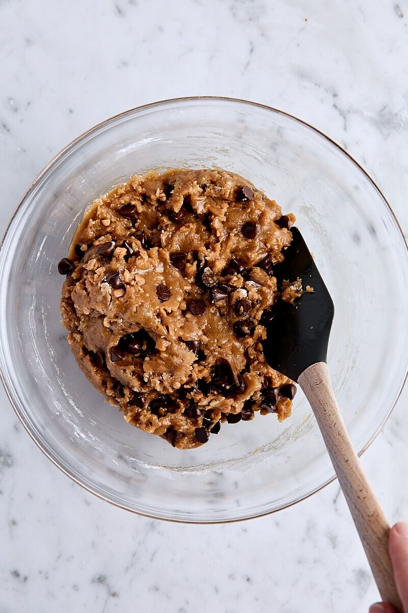Mixed chocolate toffee blondie batter in glass bowl with spatula