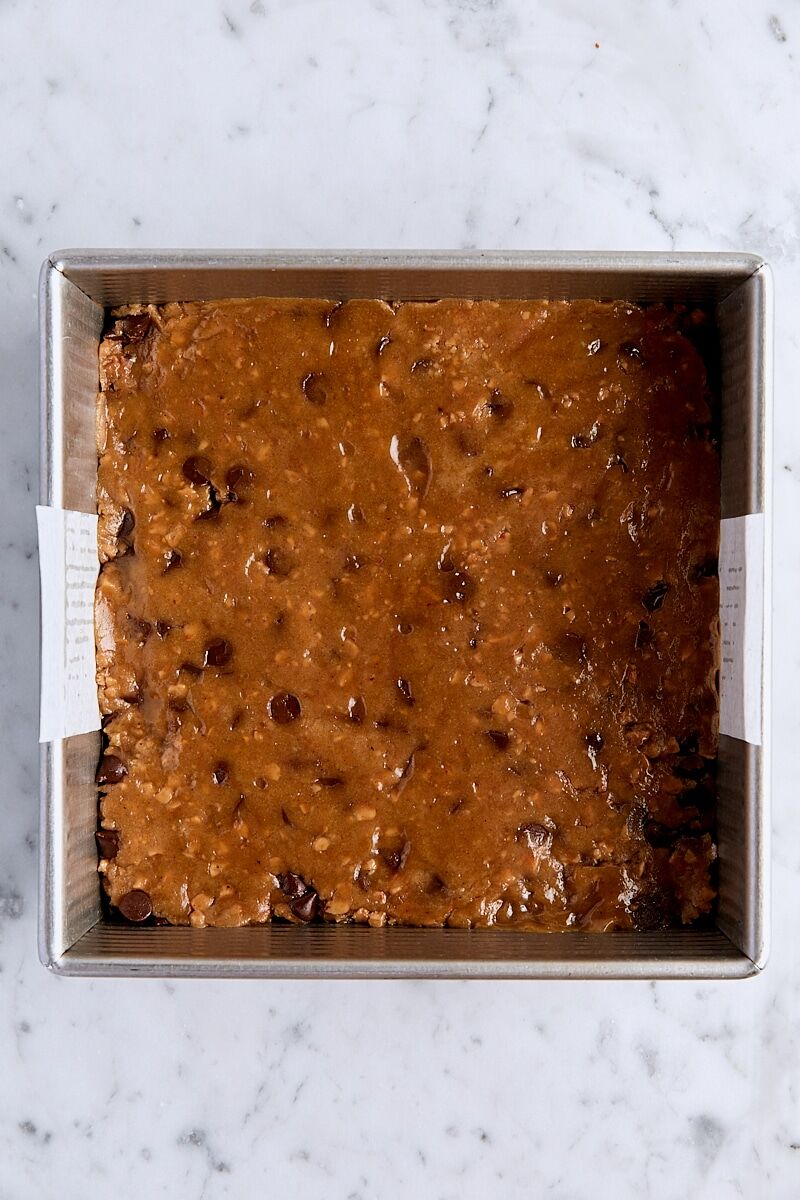 Chocolate toffee blondie batter in parchment-lined square pan
